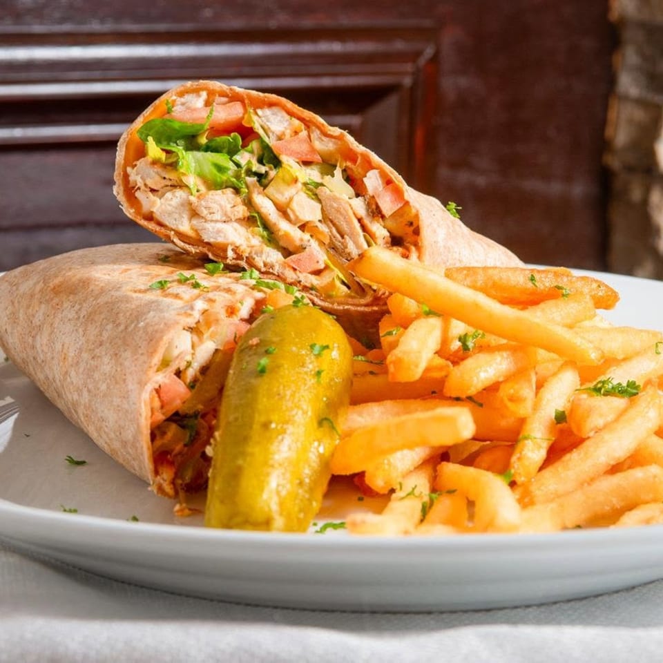 Chicken shawarma wrap with lettuce, tomatoes, and pickles, served with golden french fries.